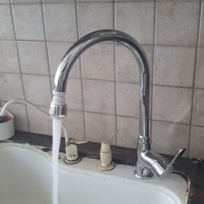 ברז מים זורם בכיור מטבח עם ידית מתכת