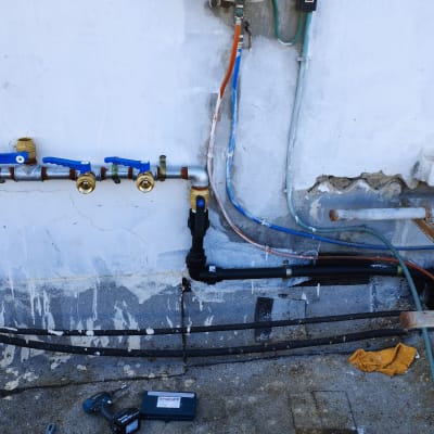 צינורות מים עם ברזים כחולים וכלי עבודה על הרצפה