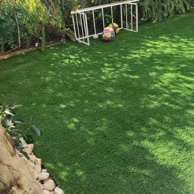 דשא סינתטי עם אבנים ועצים מסביב