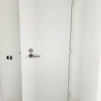 דלת לבנה עם ידית מתכת על רקע קיר לבן