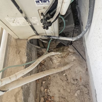 יחידת מיזוג אוויר עם צינורות וחיבורים על קיר חיצוני