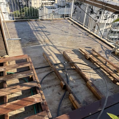 עבודת איטום על גג עם קורות עץ וצינורות