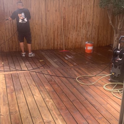 אדם מנקה דק עץ עם מכונת שטיפה בלחץ