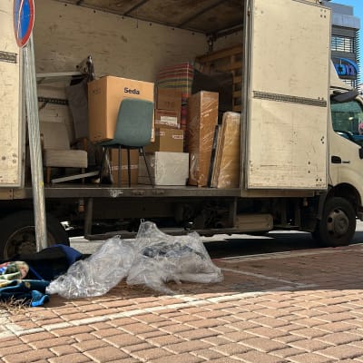 משאית פתוחה עם רהיטים וארגזים ברחוב עירוני