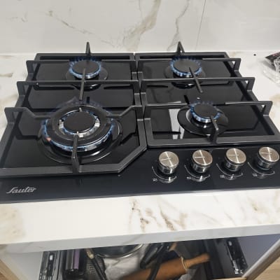 כיריים גז עם ארבעה מבערים דולקים ומתגי שליטה