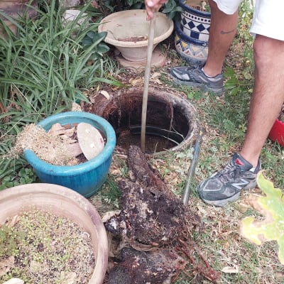 אדם מנקה בור ביוב עם מוט מתכת בגינה
