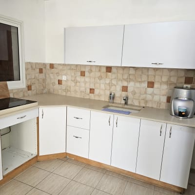 מטבח עם ארונות לבנים, כיור ובר מים