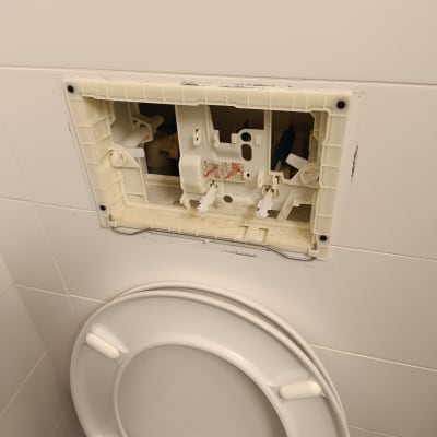 מנגנון הדחה פתוח מעל אסלה בחדר שירותים