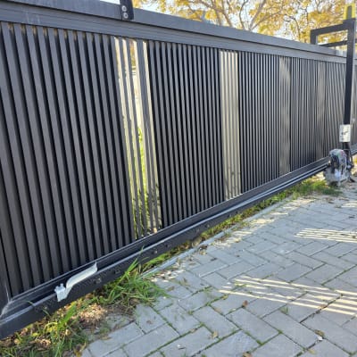 שער חשמלי שחור עם מנוע וכלים בצד