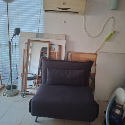 מזגן מותקן על קיר בחדר עם כורסה ושואב אבק