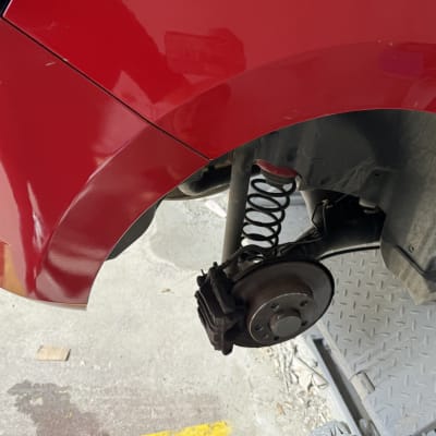 רכב אדום עם גלגל מפורק על מעלית תיקון