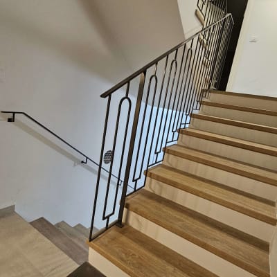 מעקה מתכת מעוצב על מדרגות עץ