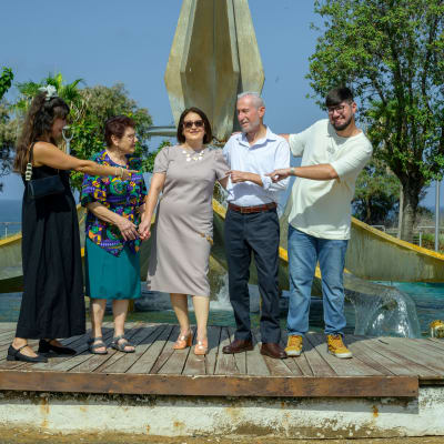 קבוצה של אנשים עומדת על במה עץ ליד מזרקה