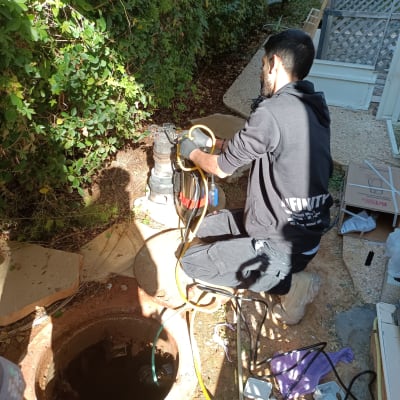 אדם עובד על מערכת ביוב עם כלים וצינורות