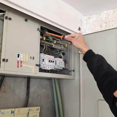 חשמלאי עובד על לוח חשמל עם מברג