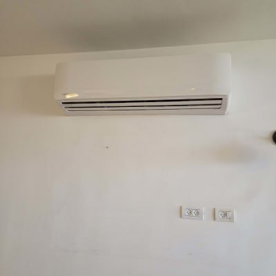מזגן מותקן על קיר לבן עם שקעים חשמליים