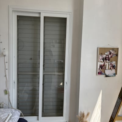 חלון זכוכית עם תריסים, סולם ותמונות על הקיר