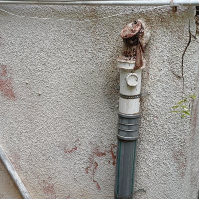 צינור מים מחובר לקיר עם סימני חלודה