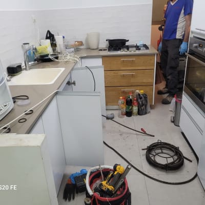 כלי עבודה של אינסטלטור במטבח, כולל מקדחה וצינור ניקוז