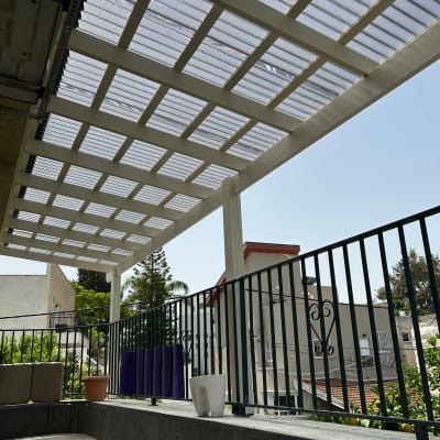 פרגולה מעץ עם גג שקוף מעל מרפסת