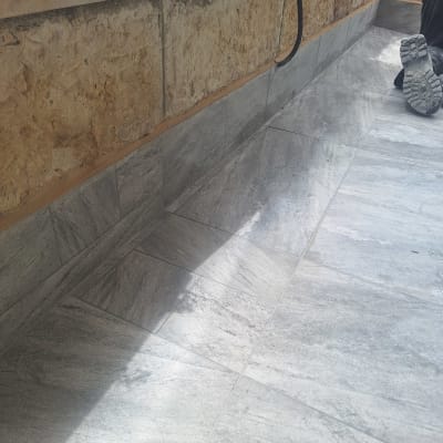 רצפה עם אריחים ואיטום ליד קיר אבן