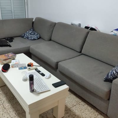 ספה אפורה עם כריות ושולחן עם מוצרי ניקוי