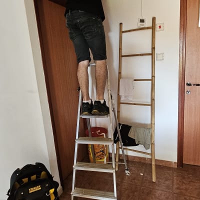 אדם על סולם מתקין מזגן בתקרה