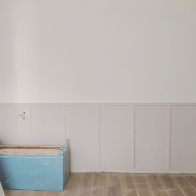 קופסה כחולה על רצפת עץ ליד קיר לבן