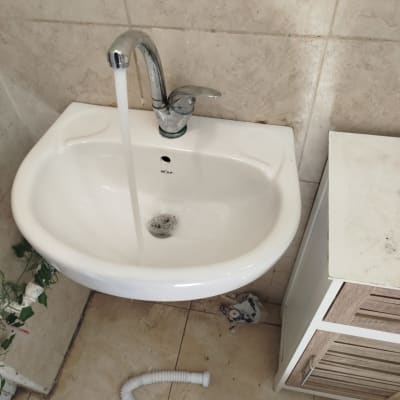 כיור עם ברז פתוח וצינור גמיש על הרצפה