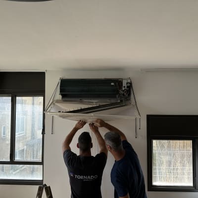 שני אנשים מתקנים מזגן תלוי על קיר