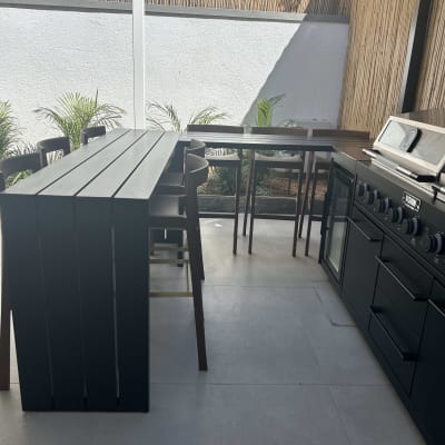 מטבח חוץ עם שולחן וכיסאות, גריל ותנור.