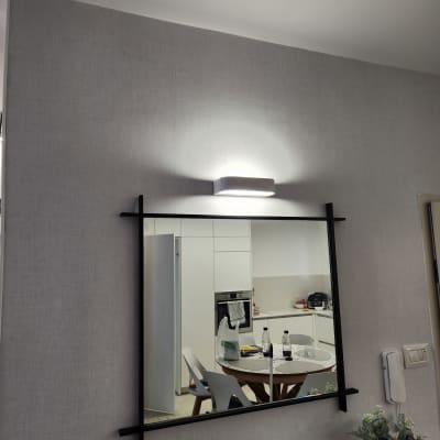 מראה עם מסגרת שחורה על קיר עם מנורה מעל