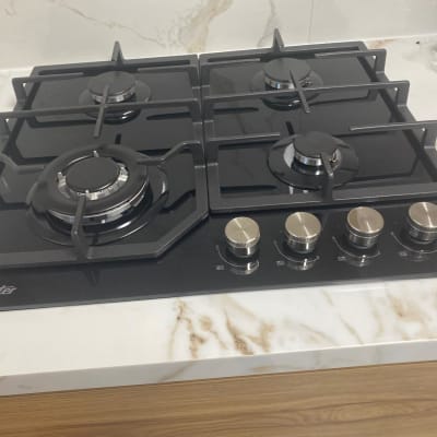 כיריים גז שחורות עם ארבעה מבערים וכפתורי שליטה כסופים