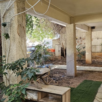 חצר עם צמחייה, כבלים חשמליים ורהיט עץ