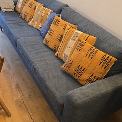 ספה כחולה עם כריות כתומות ודוגמה גיאומטרית