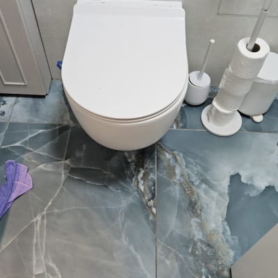 אסלה עם רצפת שיש וכלי ניקוי בשירותים