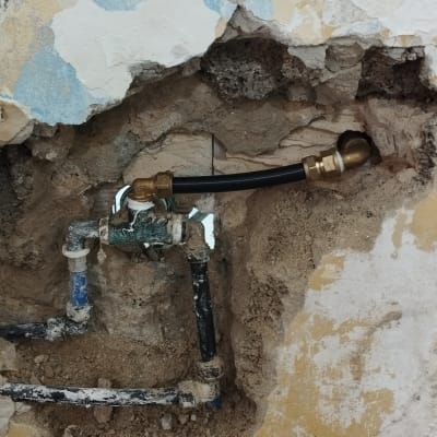 צנרת מים חשופה בקיר עם חיבורים ותיקונים