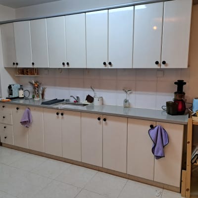 מטבח עם ארונות לבנים, כיור וכלי מטבח על השיש