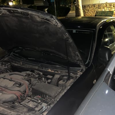 מכונית עם מכסה מנוע פתוח בלילה ברחוב