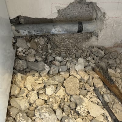 צינור מתכת בקיר עם אבנים וכלי עבודה