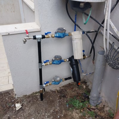 צנרת מים עם ברזים ומד מים על קיר חיצוני