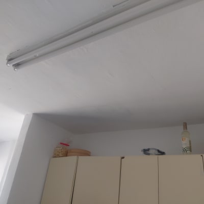 תקרה וקיר שגרתיים שנצבעו בלבן מעל ארונות מטבח