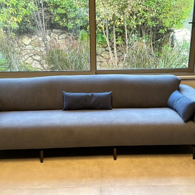 ספה אפורה עם כריות קטנות על משטח מרוצף