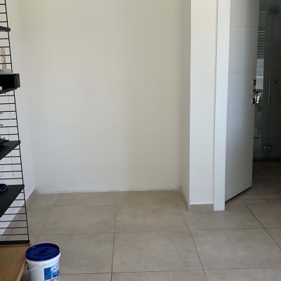 קיר לבן עם דלי צבע על הרצפה