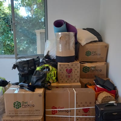 קופסאות קרטון עם לוגו Get Packing ו-Get Storage, מזוודה ותיקים