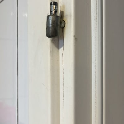 ציר מתכת על דלת עץ לבנה עם סדק