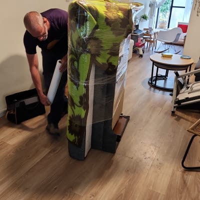 אדם עוטף רהיט בניילון נצמד למעבר דירה