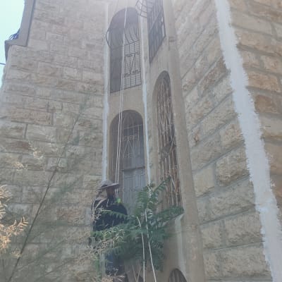 אדם עובד על איטום קיר חיצוני עם חומר לבן