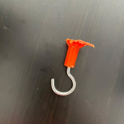 וו מתכת עם תושבת פלסטיק כתומה על רקע כהה