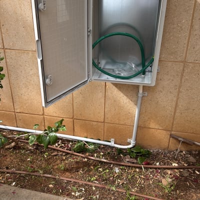 ארון חשמל פתוח עם צינור ירוק ליד קיר